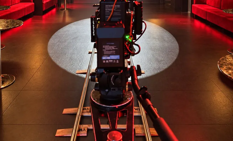 A cinema camera on a dolly track in the main room, red light on the floor