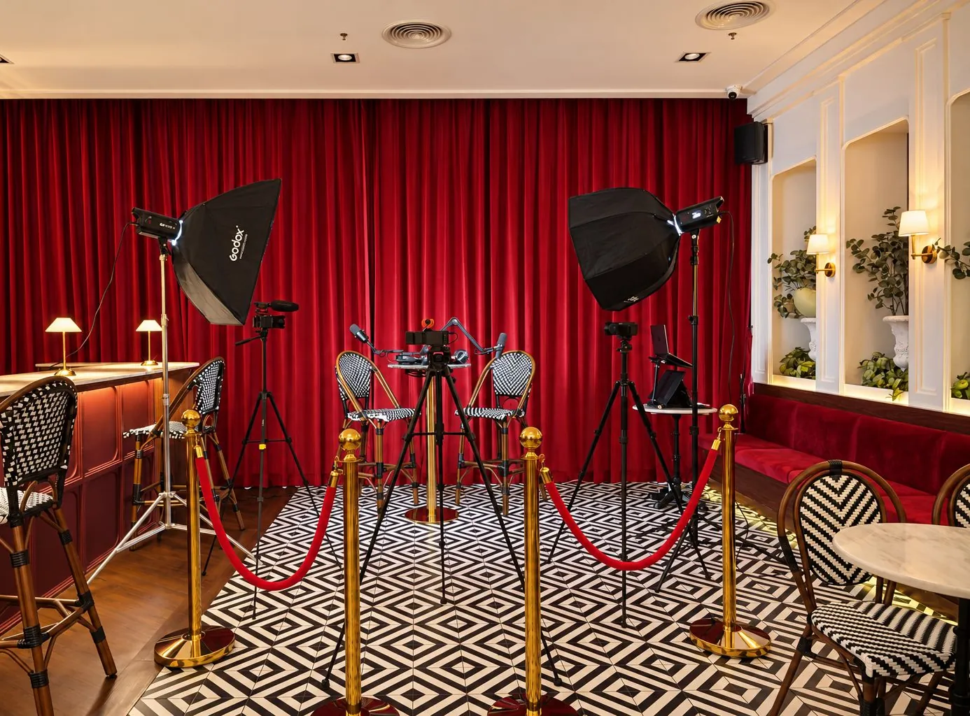 Podcast set with two chairs, microphones, cameras and softbox lights in front of a red curtain